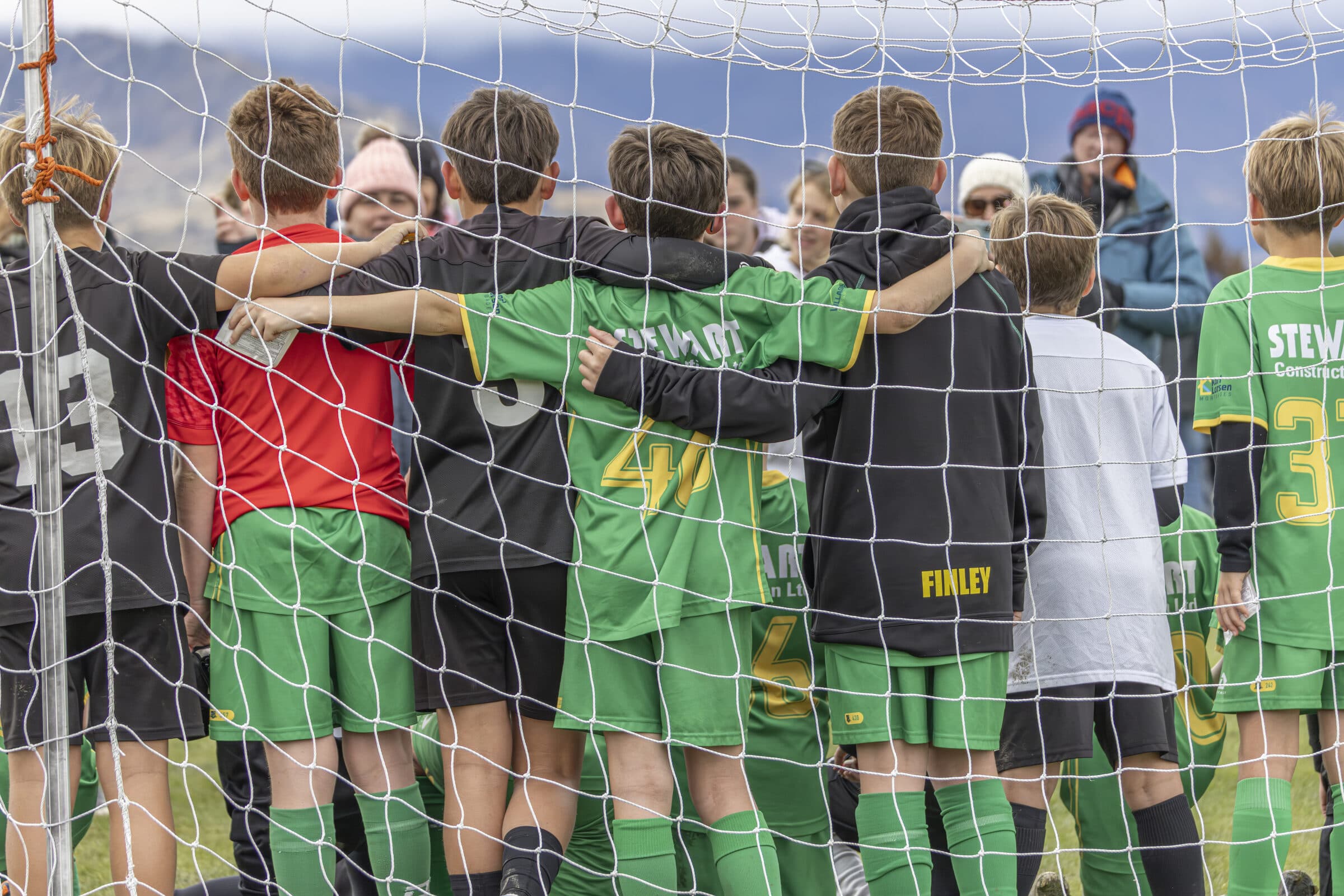 Two mingled teams standing arms-around-shoulders behind the goal at a Global Games event